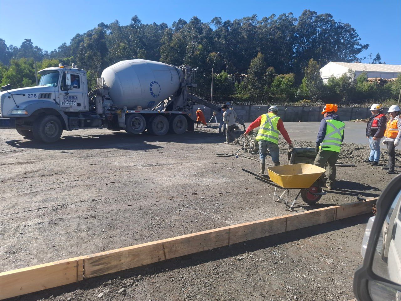 Camión mixer hormigonando patio industrial con cuadrilla