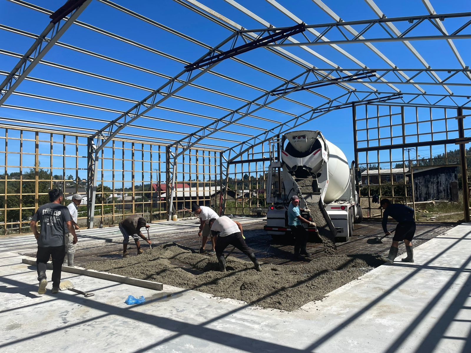 Equipo vaciando hormigón premezclado desde camión mixer en obra industrial